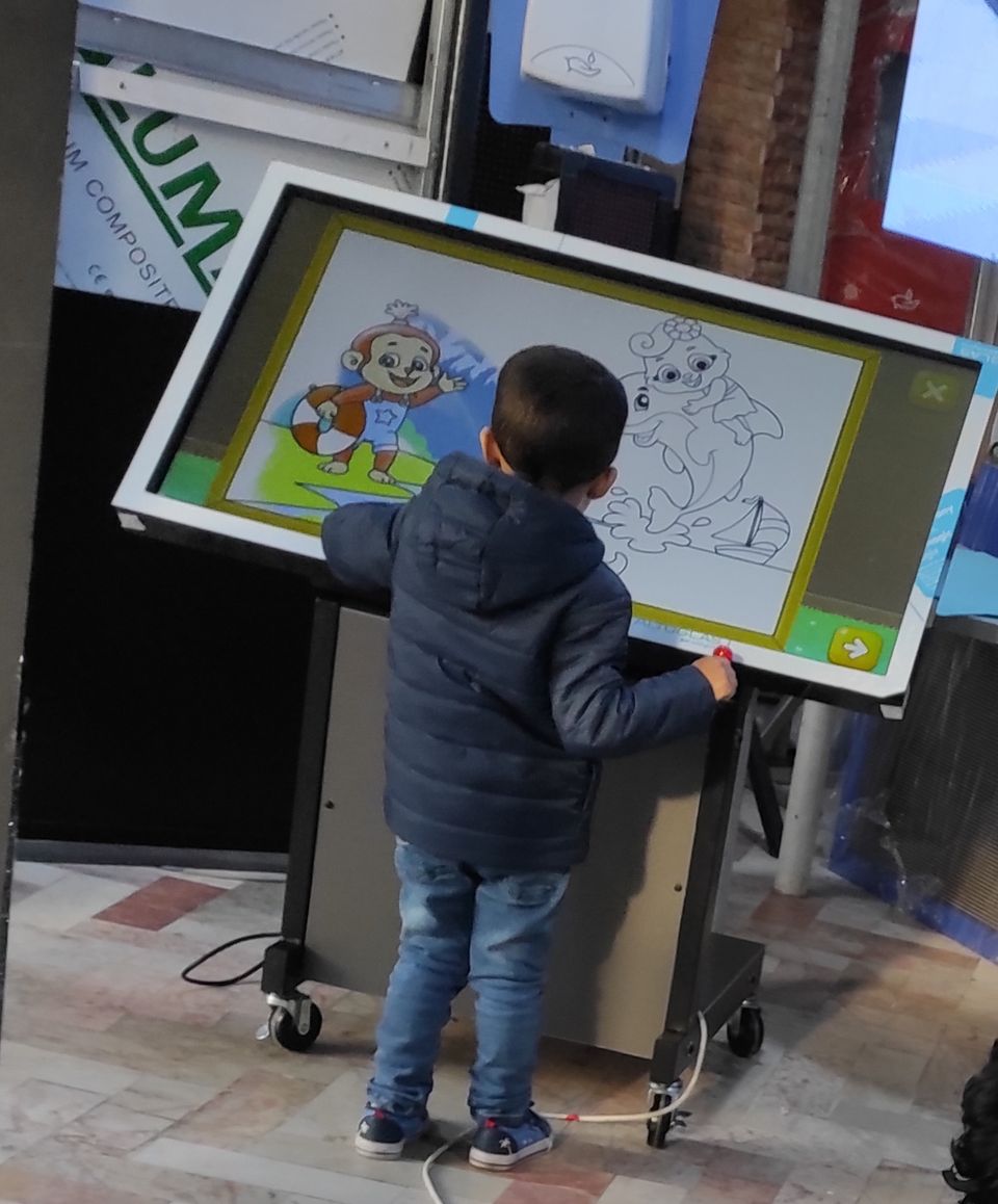 طفل يستعمل كشكاً تفاعلياً للرسم باللمس